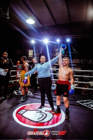 A boxer raises a glove in the ring beneath the arena lights.