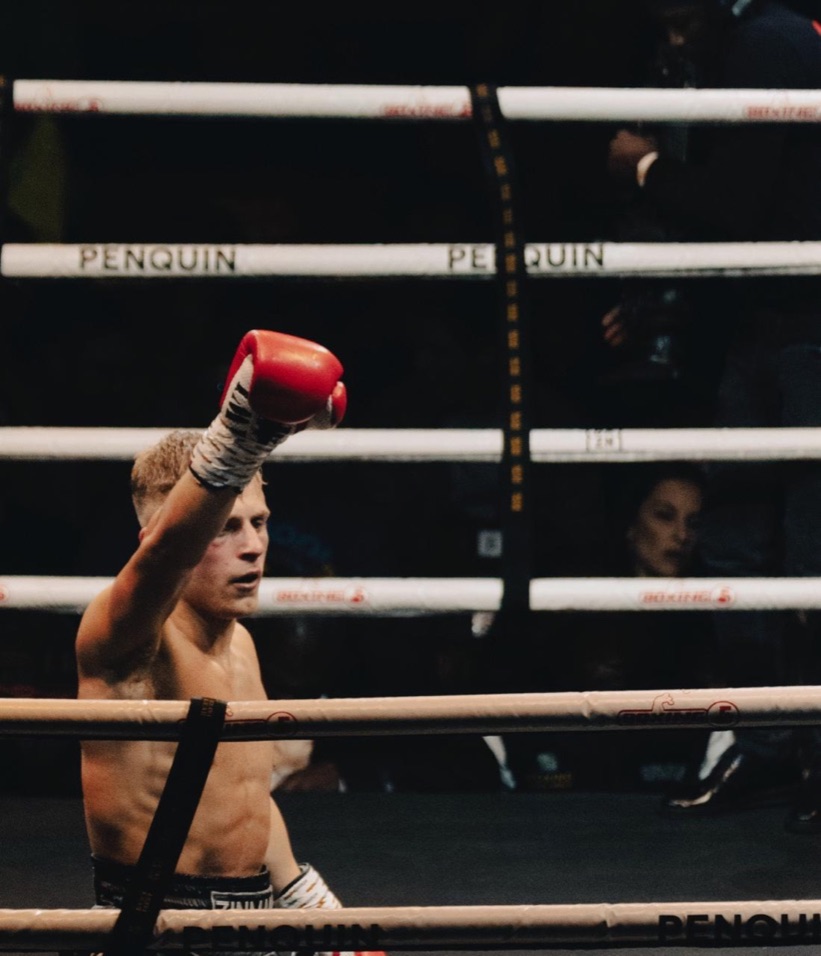 A boxer raises a red glove above the ring ropes.