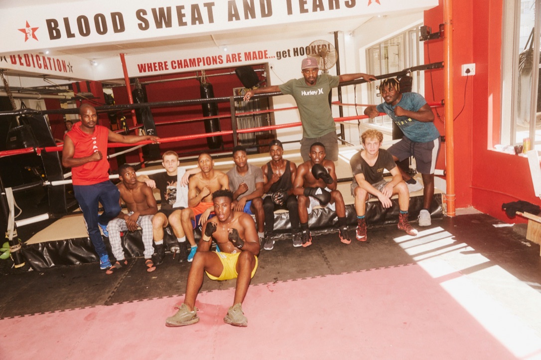 Young boxers pose together in front of a gym ring.