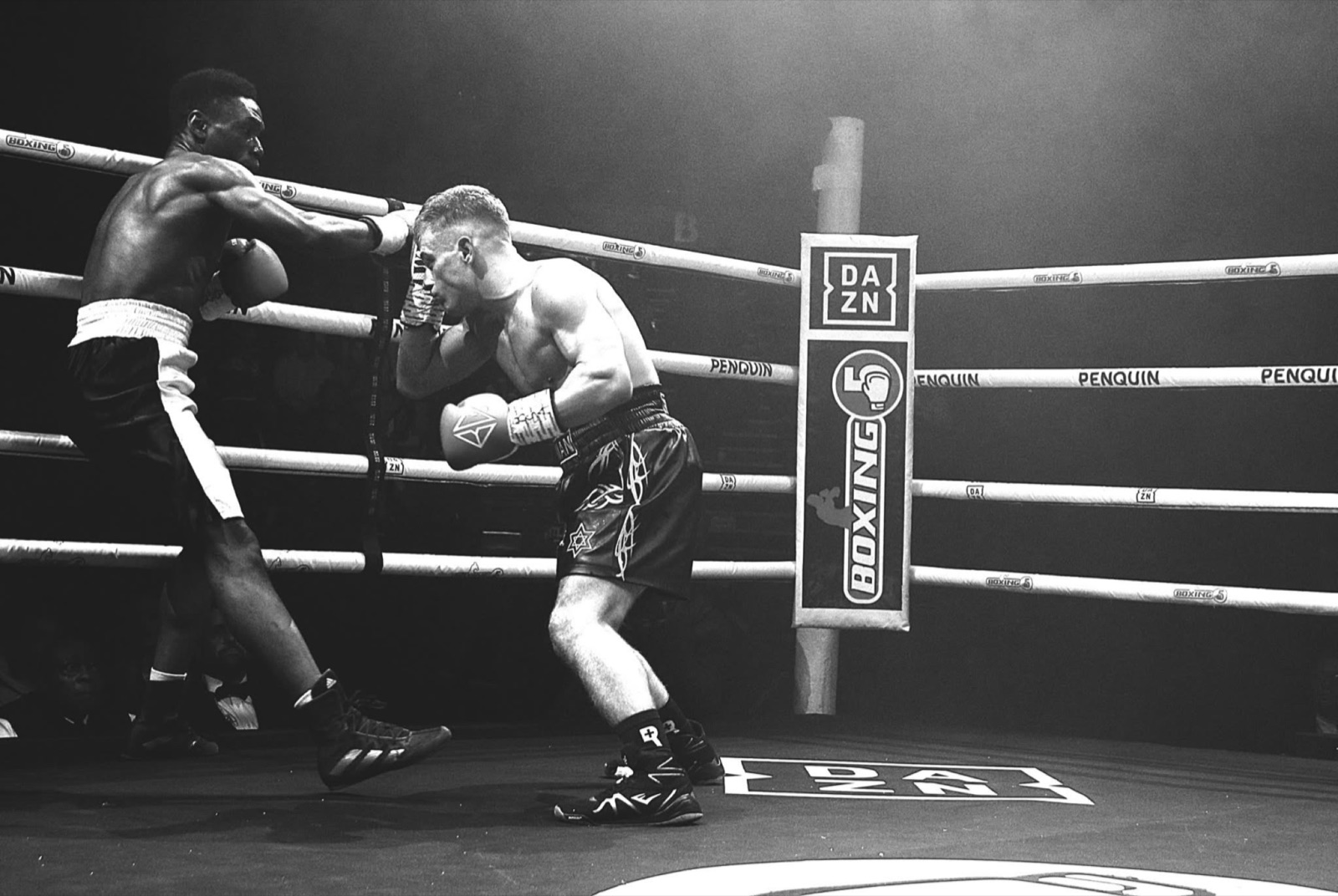 Black-and-white action shot of two boxers exchanging punches in the ring.