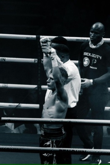 Black-and-white ringside view of two boxers facing each other.
