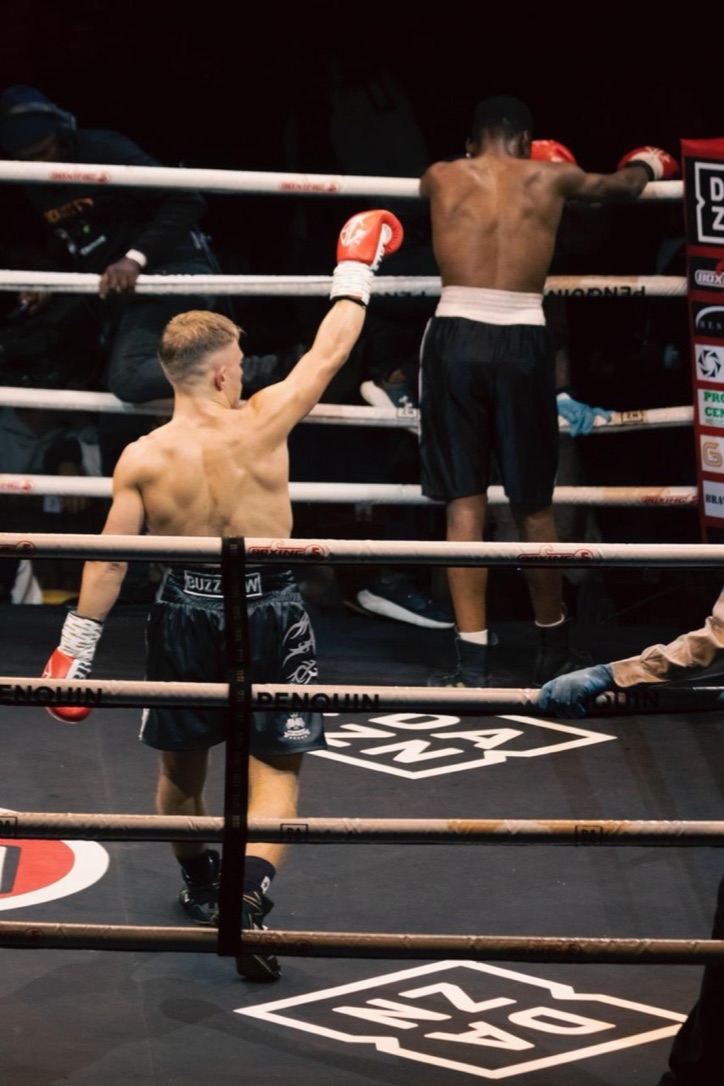 A boxer raises one glove while his opponent faces the corner.