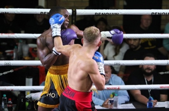 Two boxers exchange punches in a brightly lit ring.