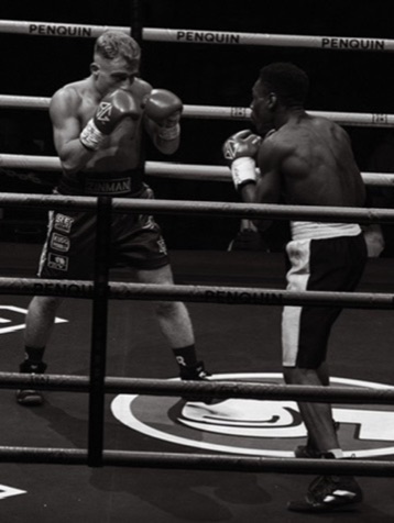 Black-and-white close-up of two boxers trading punches.
