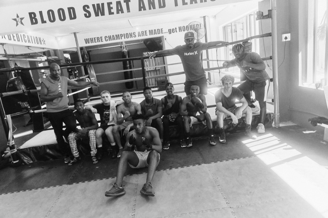 Black-and-white group portrait of a boxing team gathered around the ring.