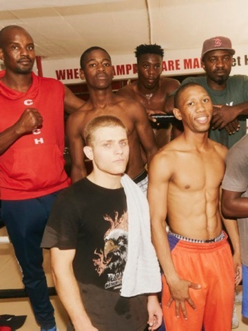 A fight team gathers behind a seated boxer for a group portrait.
