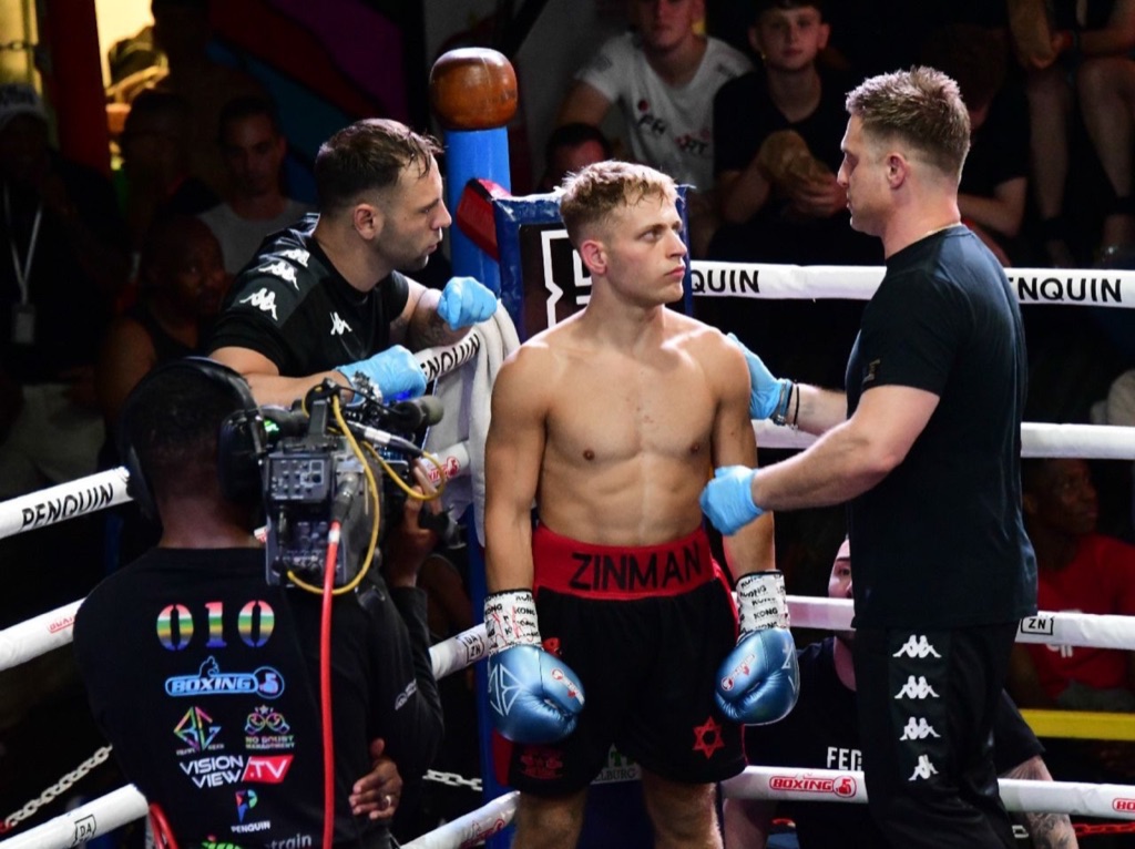 A boxer stands in his corner with three members of his team.