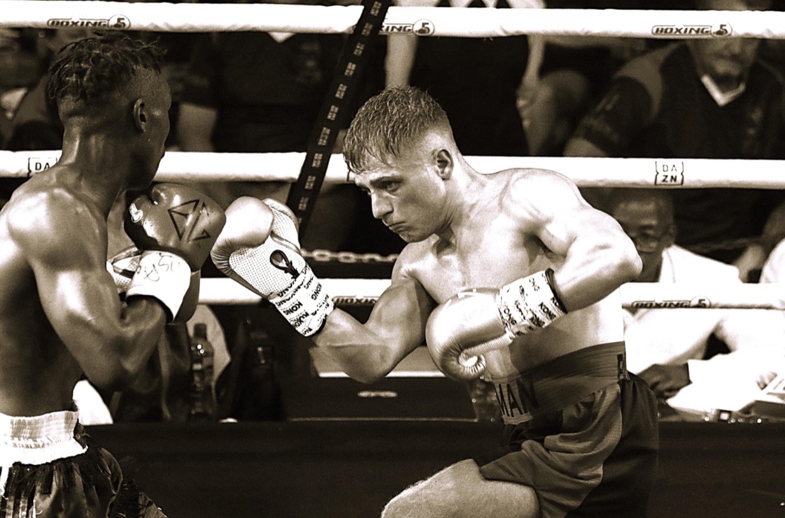 Sepia-toned ringside view of two boxers exchanging punches.