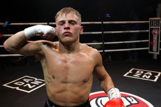 A boxer raises both arms in the ring after a bout.