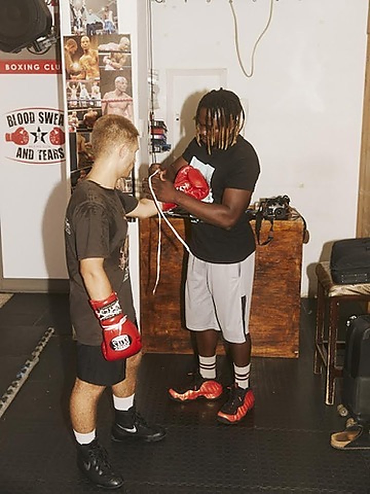 A coach helping a beginner get their gloves on before a boxing session