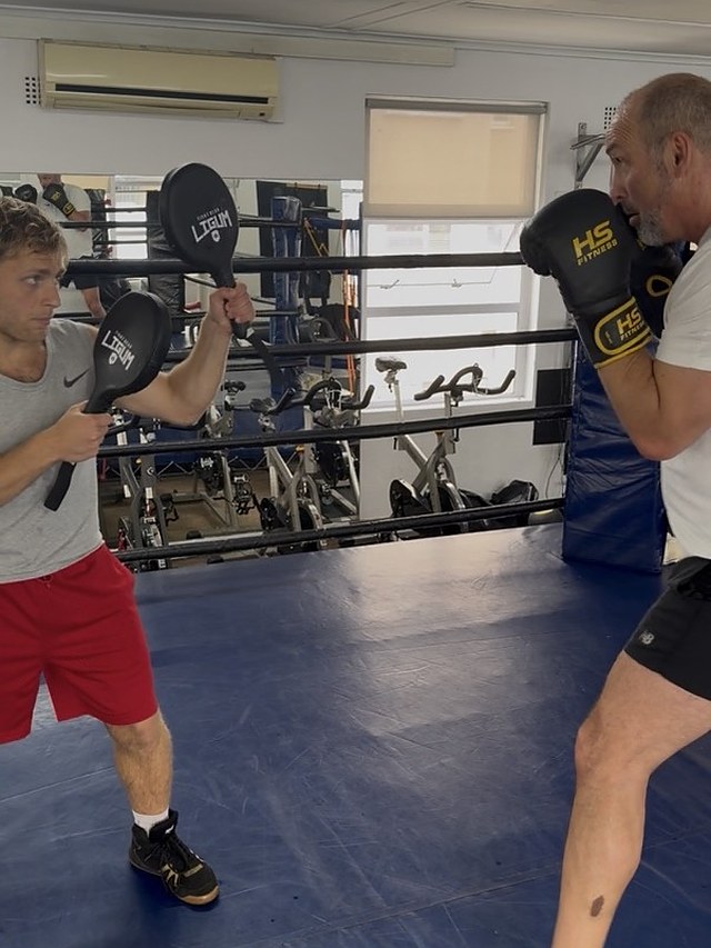 Doron coaching a client on the pads in the ring at Top Floor Boxing