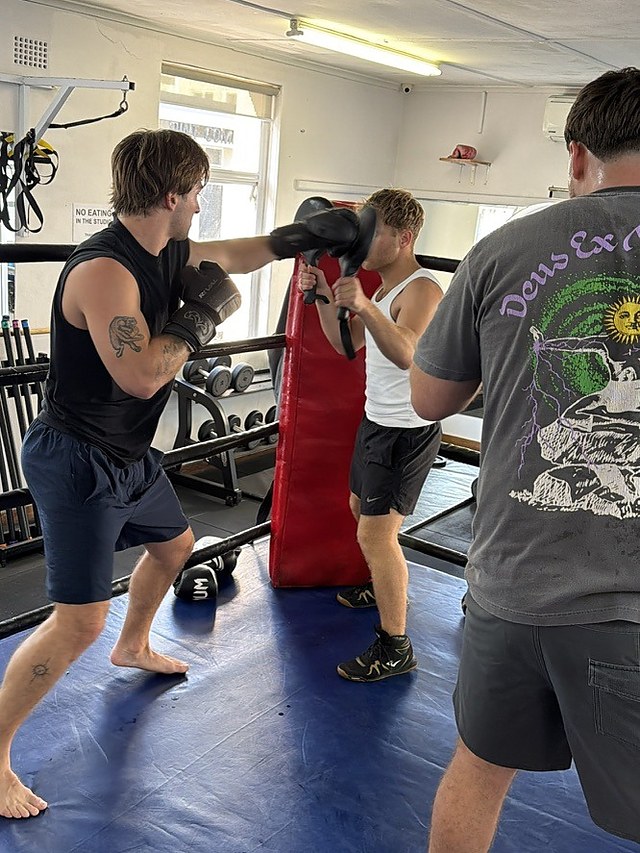 Clients taking turns on the pads during a private group boxing session.