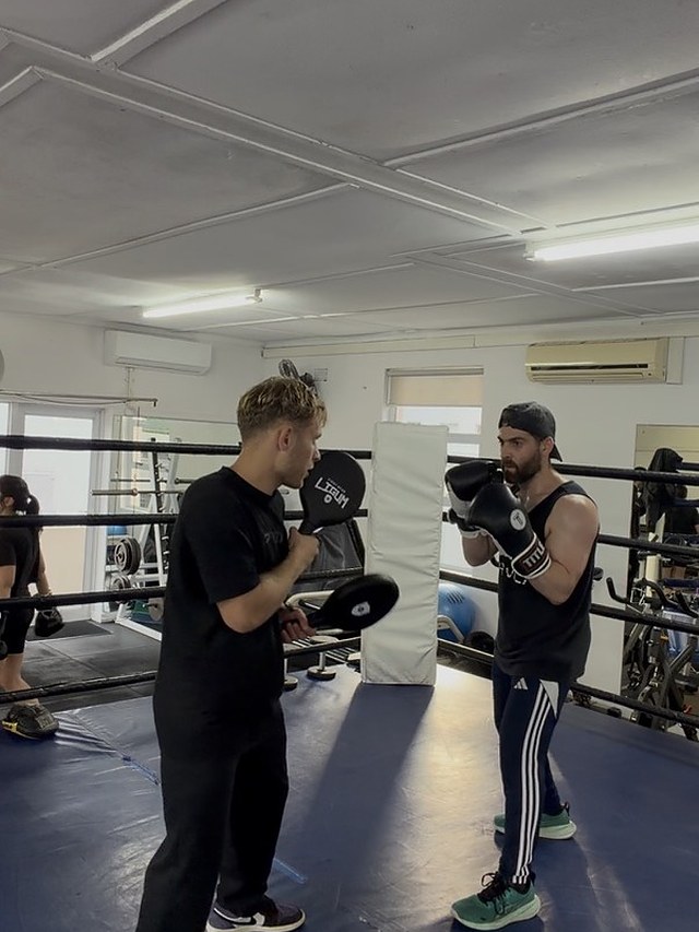 A beginner holding guard while Doron sets up the next combination on the pads.