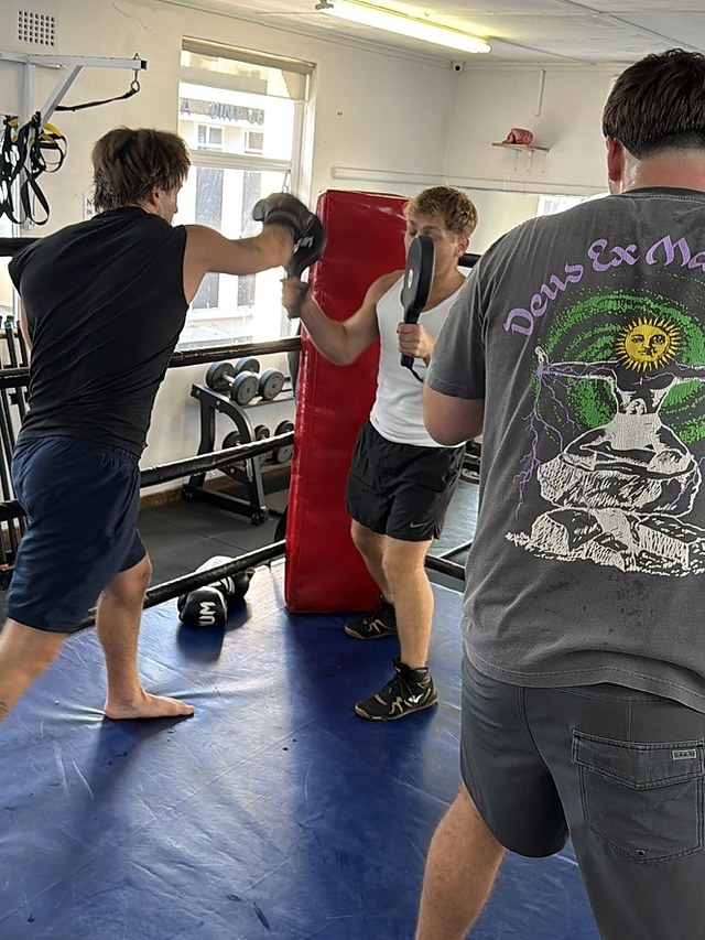 Partner pad rounds during a private group boxing session at Top Floor Boxing